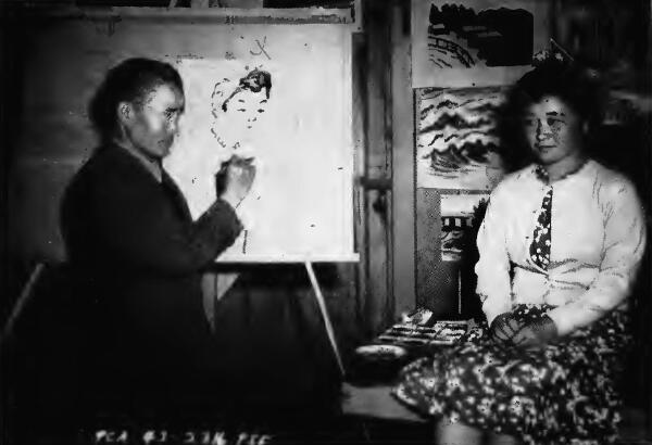 A Japanese artist sketching girl posed against a background of landscapes at Tanforan (California) Assembly Center